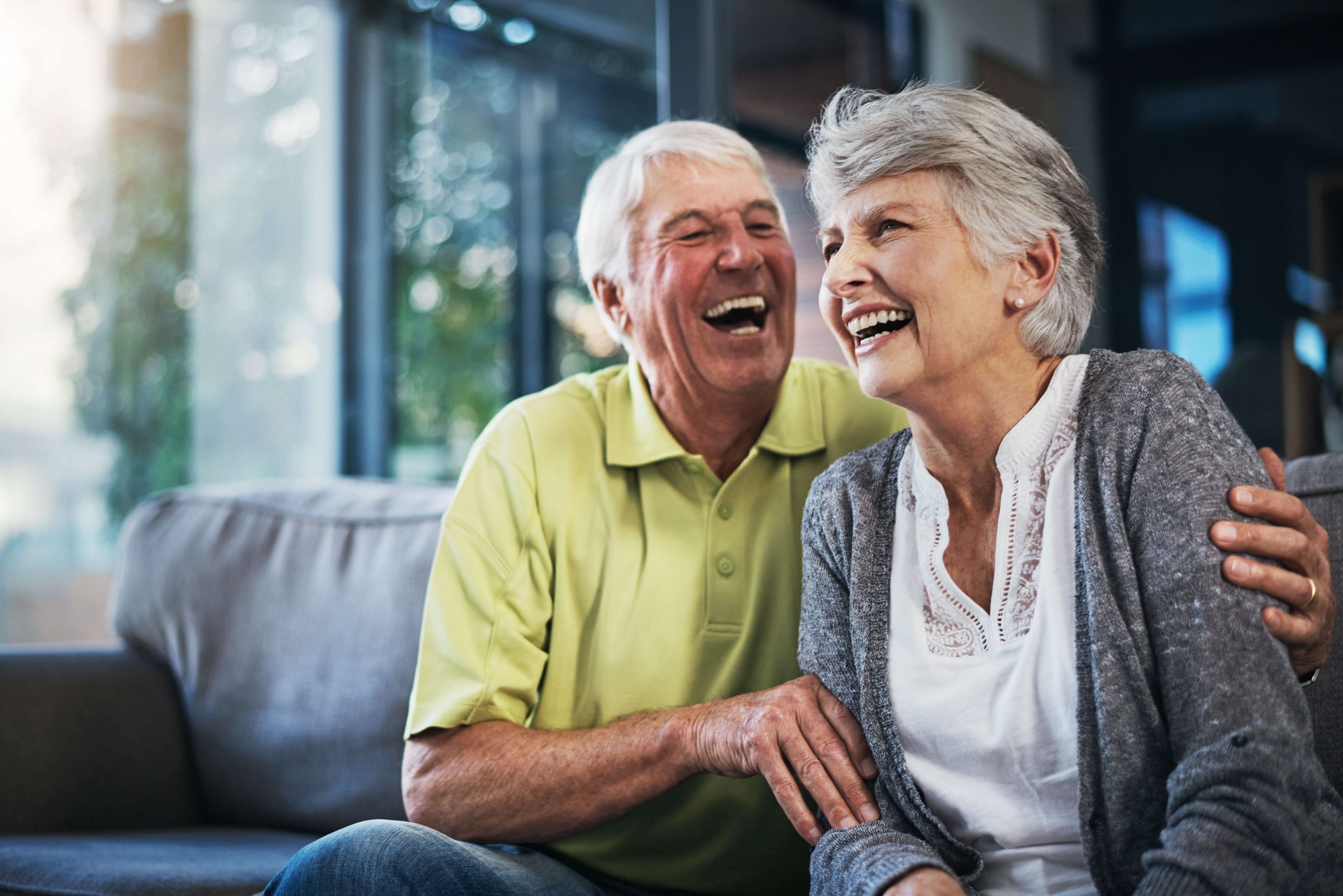 Older couple sitting on a couch and laughting