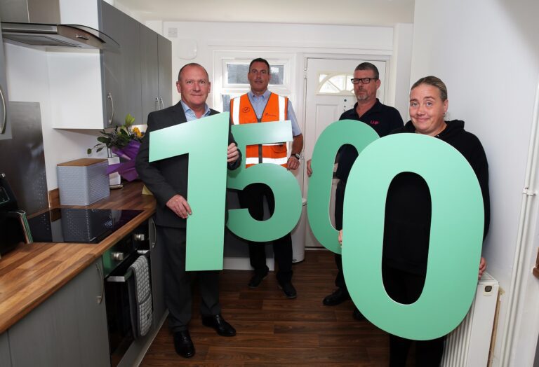 Two people from Equans and a surveyor from LHP visit Louise Spalding, an LHP customer in Immingham, to celebrate her home being the 1500th to receive a new kitchen through an investment programme. The people are holding large numbers showing 1500 and are standing in the new kitchen.
